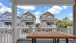A wooden deck with a table, white railings, and two-story houses in the background. - Horizon Dune Pet Friendly House Walk to Beach (Myrtle Beach)