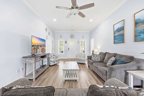 A living room with a ceiling fan, a television, a coffee table, and two sofas. - Hibiscus Hideaway Walk to Beach and Main Street (North Myrtle Beach)
