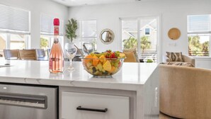 Une cuisine moderne dotée d’un grand îlot central, d’une bouteille de vin et d’un saladier rempli de fruits.