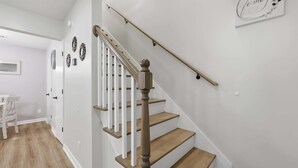 A staircase with wooden steps and white railings, leading to a landing with a wall-mounted sign. - Seabreeze Retreat Modern Home Walk to Beach (Myrtle Beach)