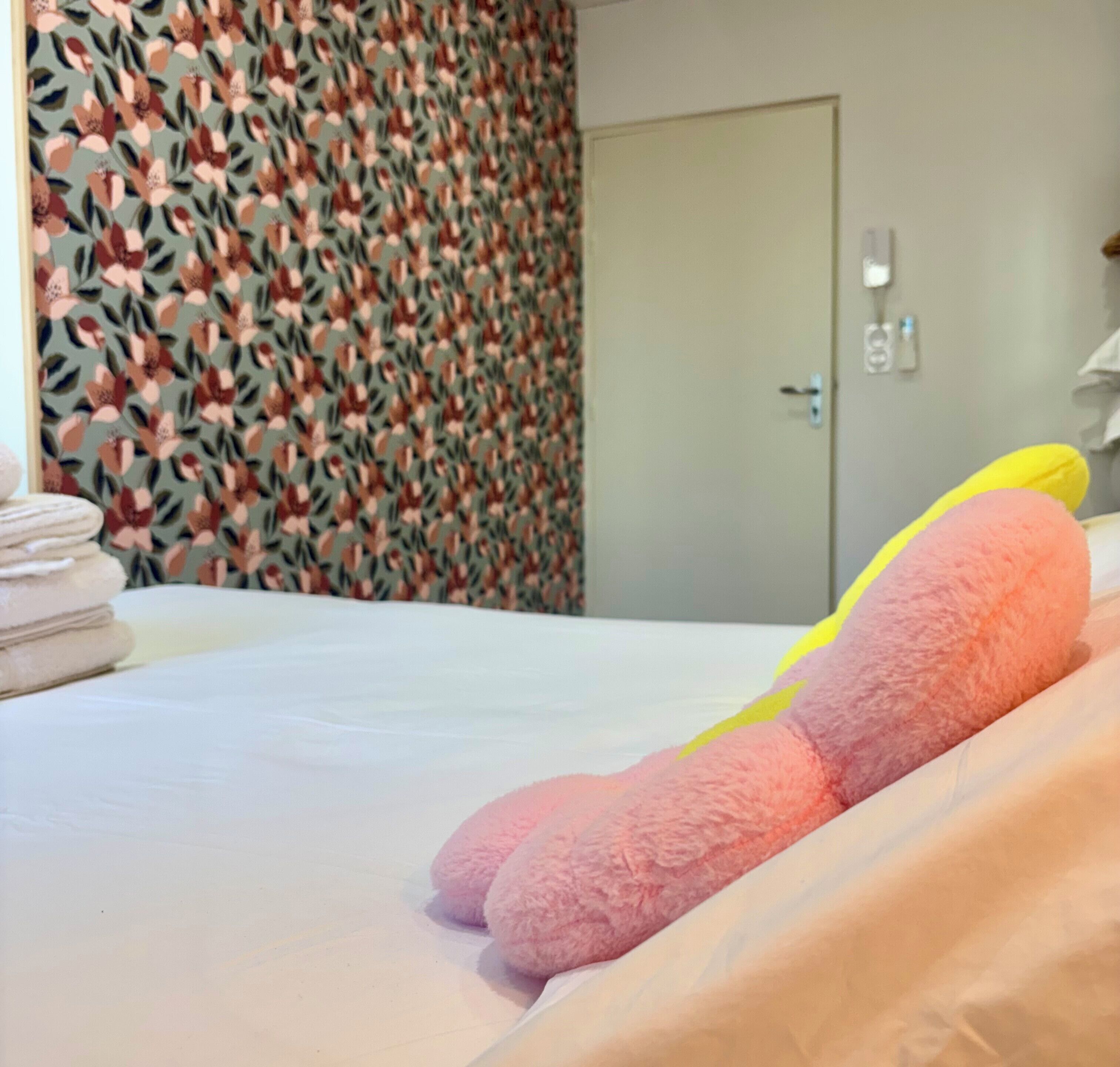 Une chambre d’hôtel avec un lit, une porte et un mur orné d’un motif floral.