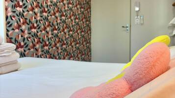 Une chambre d’hôtel avec un lit, une porte et un mur orné d’un motif floral.