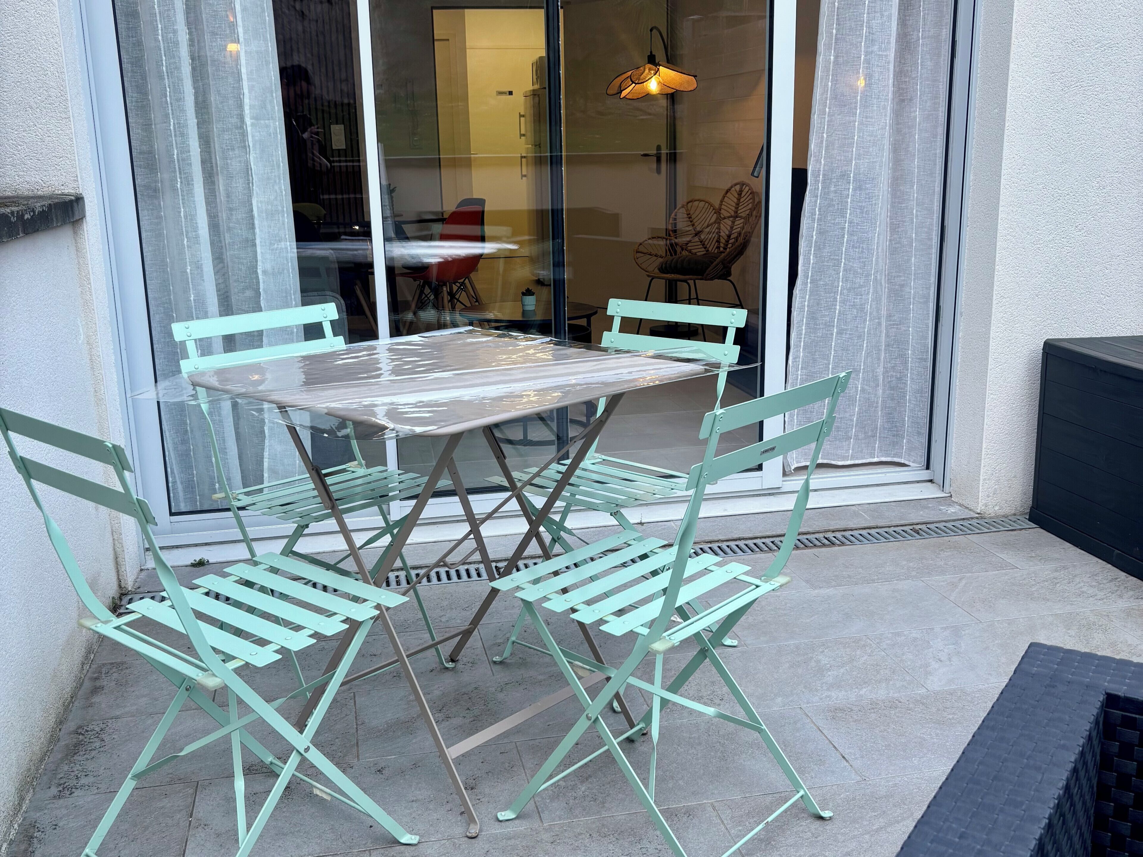 Une terrasse dotée d’une porte vitrée, d’une table et de quatre chaises.