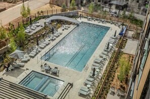 A rooftop swimming pool with lounge chairs and a glass-enclosed area.