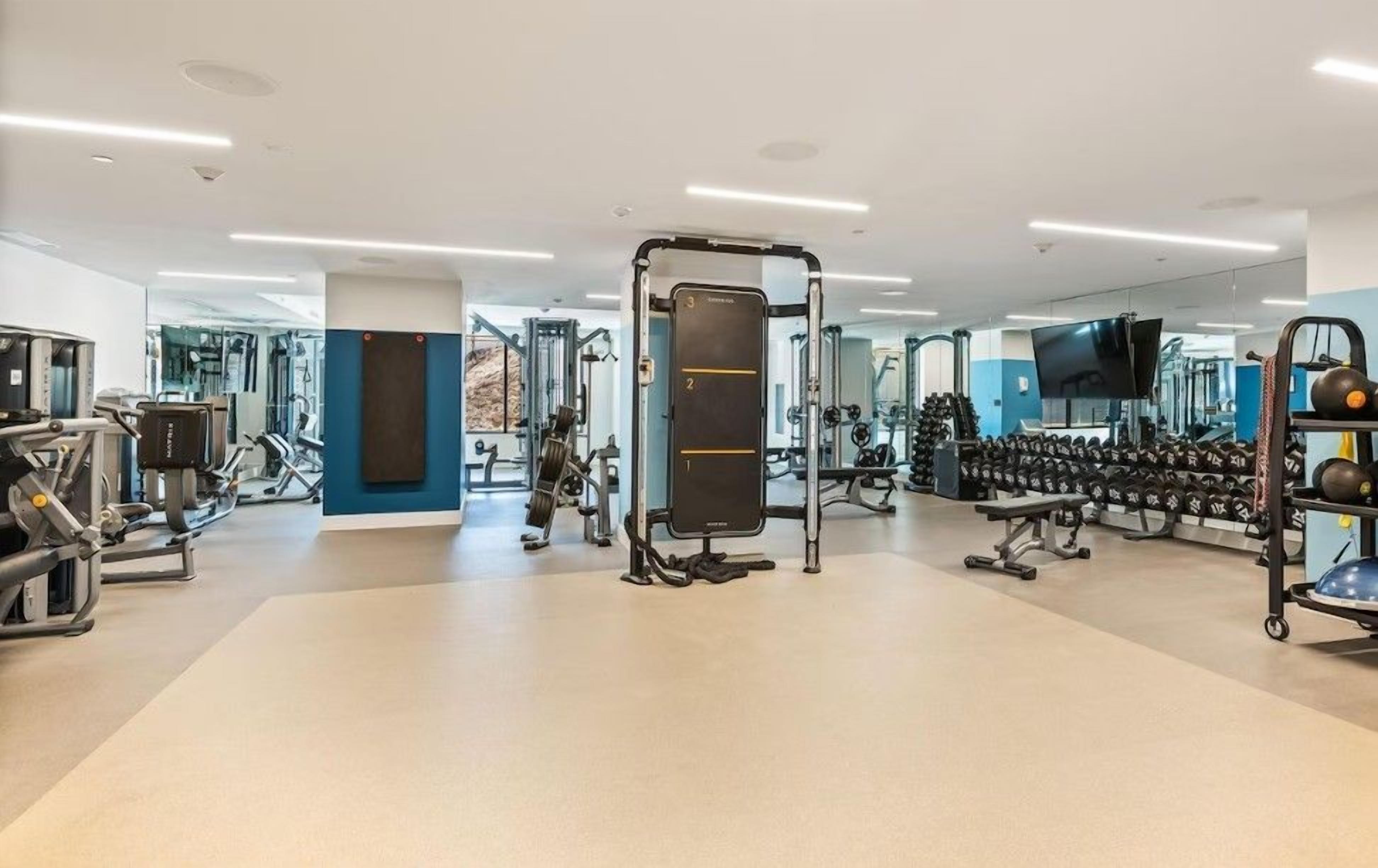 Une salle de sport moderne équipée de divers appareils d’exercice, notamment des machines de musculation et des haltères.