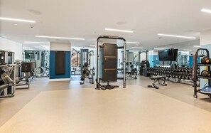 Une salle de sport moderne équipée de divers appareils d’exercice, notamment des machines de musculation et des haltères.
