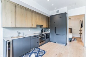 A modern kitchen with grey cabinets, a wooden countertop, and a built-in oven.