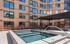 Un bâtiment moderne doté d’une piscine et d’un espace extérieur aménagé pour se détendre.