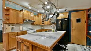 Una cocina con armarios de madera, una isla central, una estufa y un refrigerador.