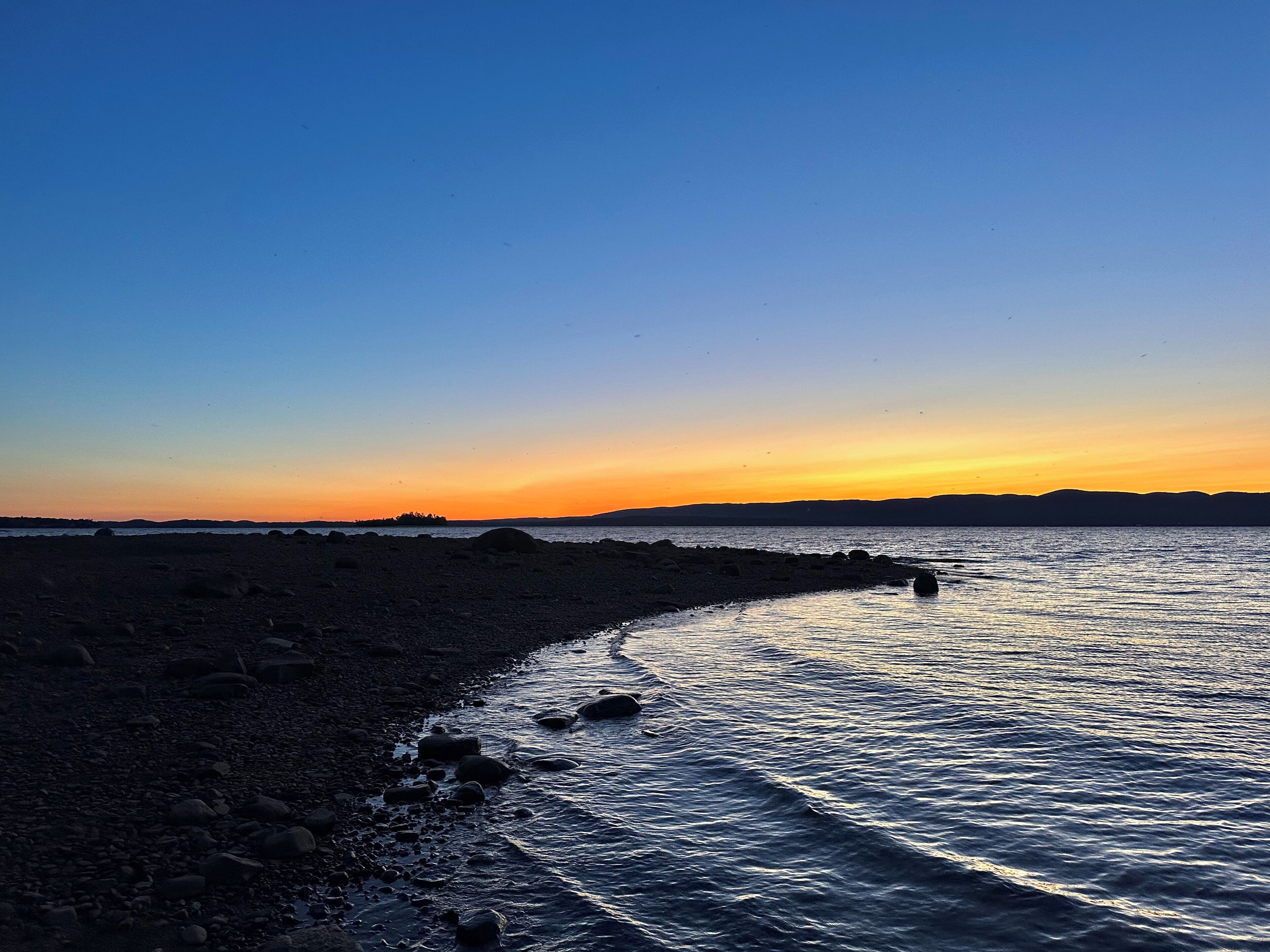 Une plage au rivage rocheux et aux eaux calmes.