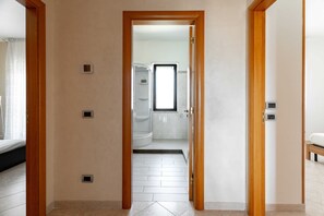 A hallway leading to a bathroom with a shower, a toilet, and a sink. - Sofia's apartment by Monholiday (Polignano a Mare)
