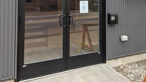 A building with a large double door, a small sign above the door, and a number '15' on the wall to the right. - American Hall Young Suite (Millersburg)
