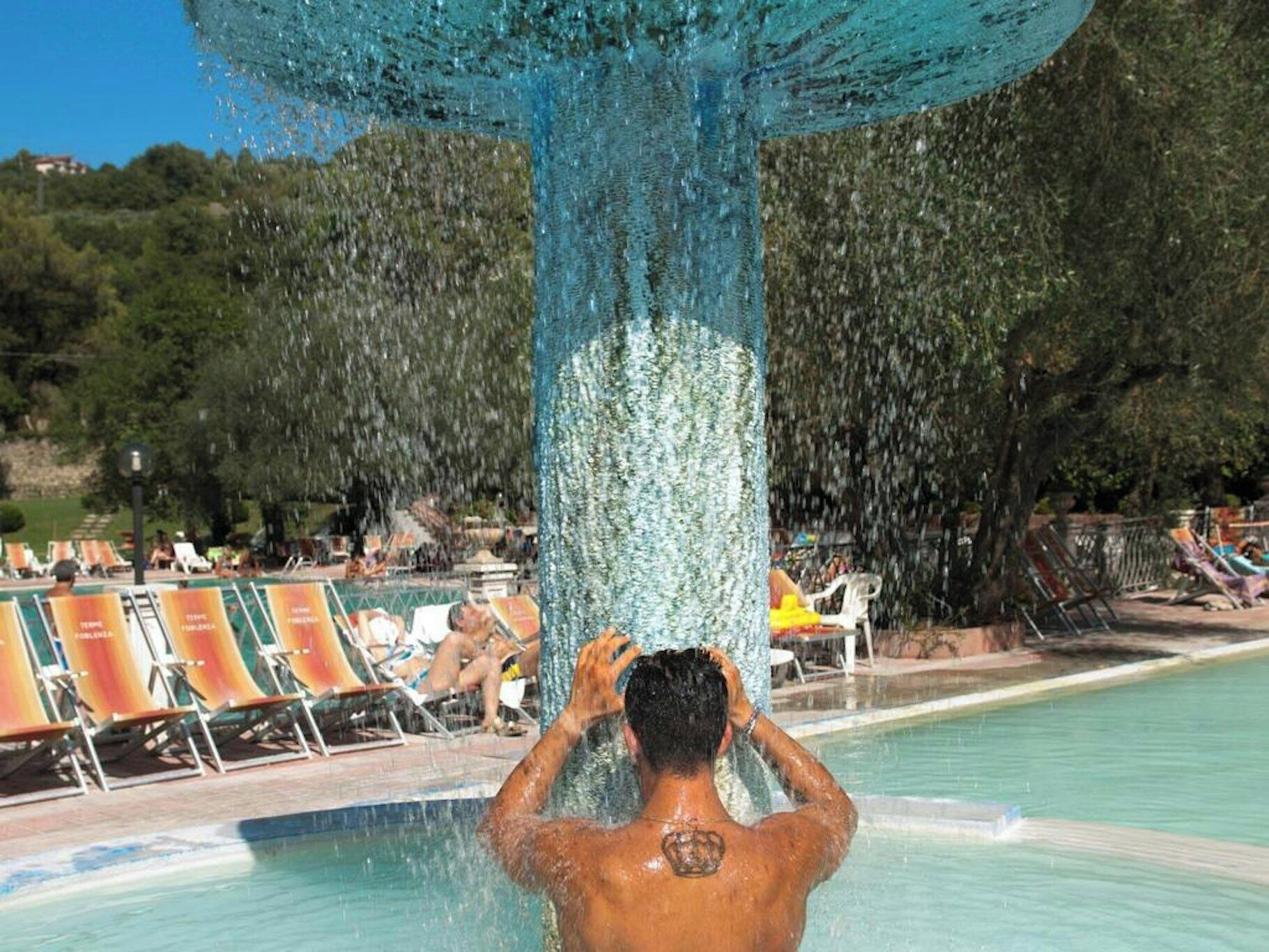 En person i en swimmingpool med en vattenfontän ovanför sig.