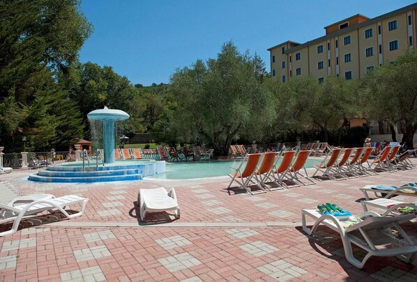 A pool area with lounge chairs, a central fountain, and a building in the background. - Hotel Terme Forlenza (Contursi Terme)