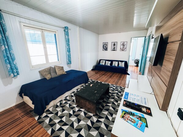 A room with a bed, a sofa, a coffee table, and a TV.