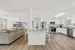 A modern kitchen with white cabinets, stainless steel appliances, and a central island with bar stools. - Wavecrest Grand with Pool Great for Groups (Surfside Beach)