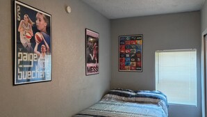 A bedroom with a bed, a poster of Paige Bueker, a poster of Lionel Messi, and a poster of NFL team logos. - THE JAX HIDEOUT 
DT studio w/shaded patio (Jacksonville)