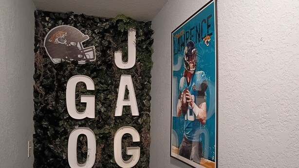 A wall with the letters 'JAGOS' and a poster of Lawrence. - THE JAX HIDEOUT 
DT studio w/shaded patio (Jacksonville)
