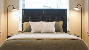 Un dormitorio con cama, una ventana con persianas y dos lámparas de noche.