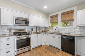 A kitchen with white cabinets, stainless steel appliances, and a wooden floor.