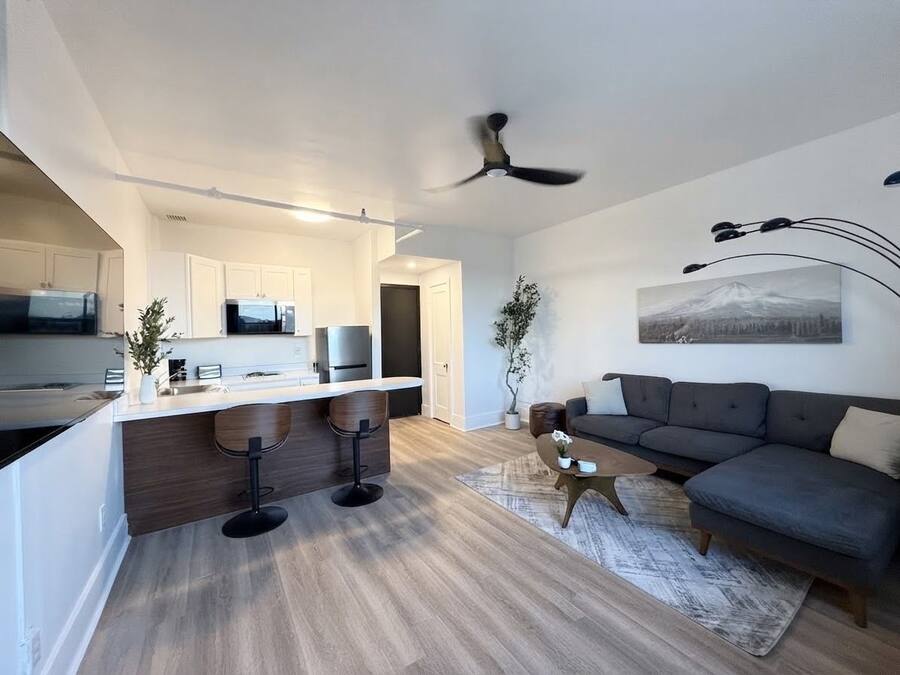 En moderne opholdsstue med et køkken, spiseplads og siddeområde med sofa og sofabord.