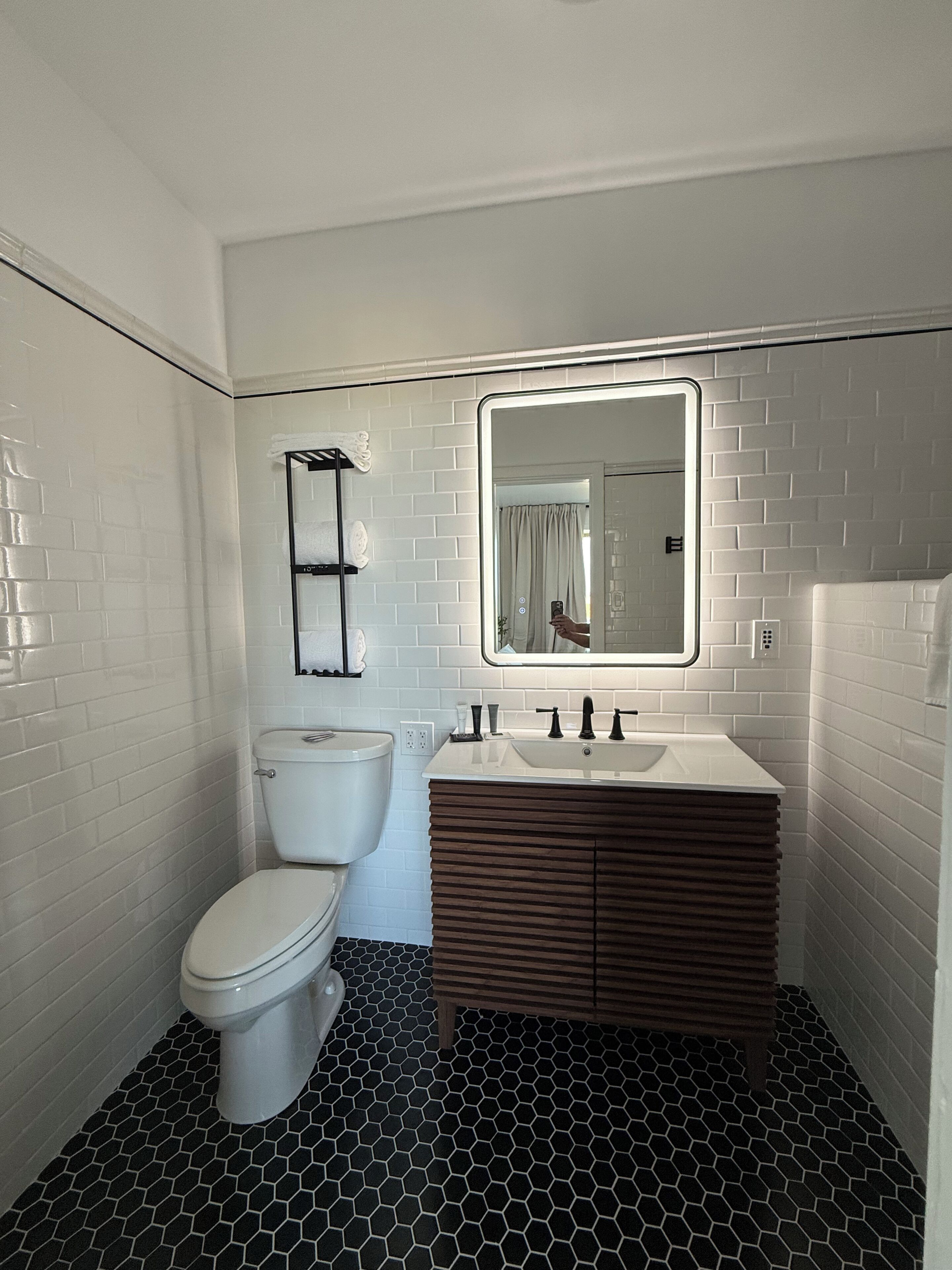 A bathroom with a toilet, a sink with a mirror, and a tiled floor.