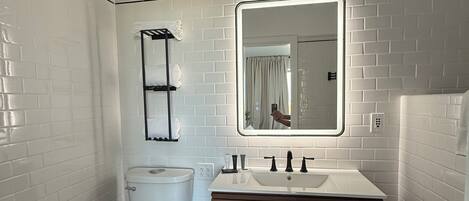 A bathroom with a toilet, a sink with a mirror, and a tiled floor.