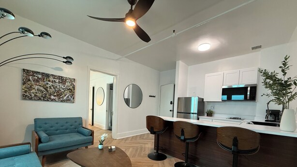 A modern living room with a sofa, coffee table, and a dining area with bar stools. - The Historic George Hotel (Klamath Falls)