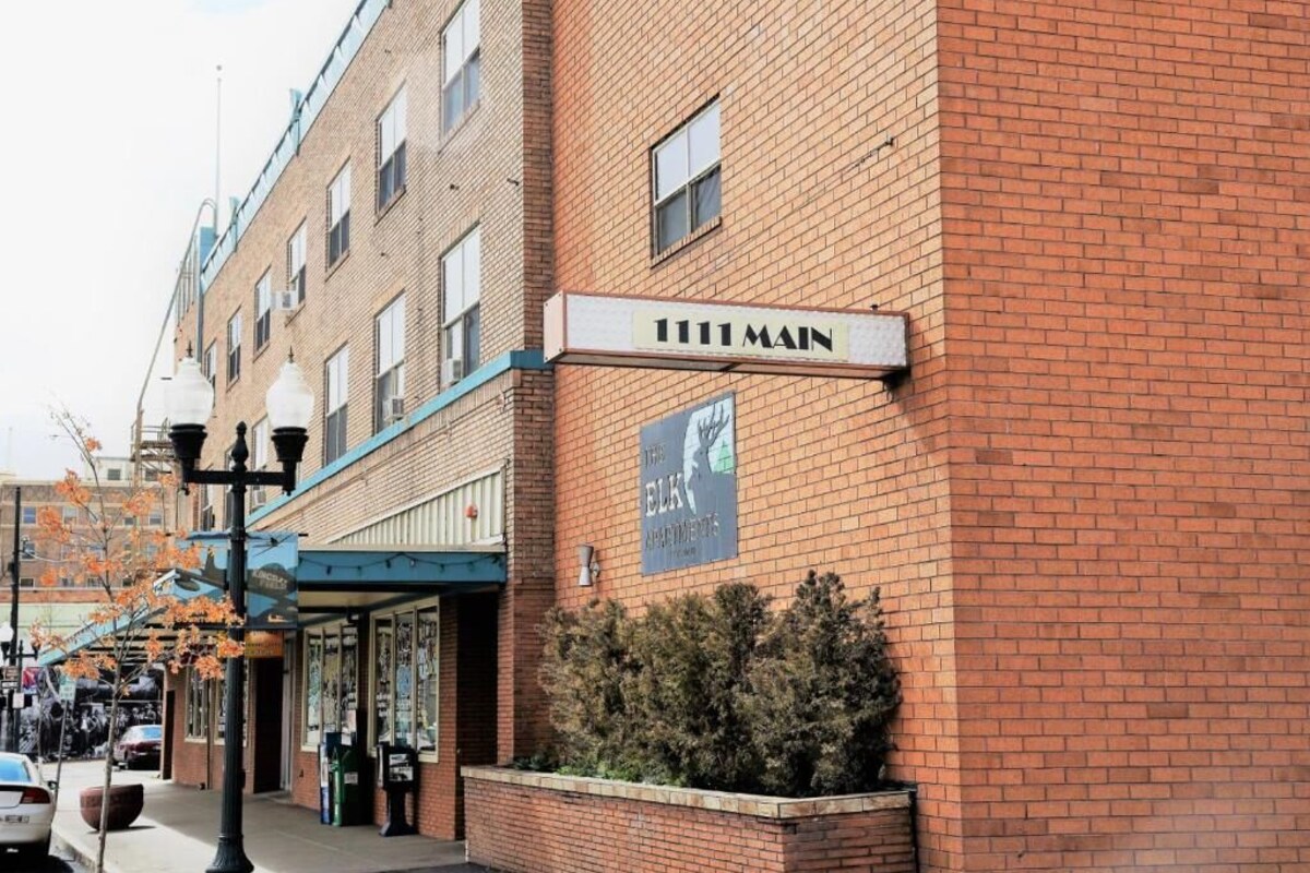 A brick building with a sign reading '111 Main' and a banner advertising 'The Elk Apartments.'