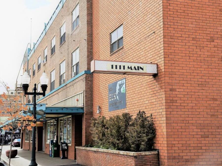 A brick building with a sign reading '111 Main' and a banner advertising 'The Elk Apartments.'