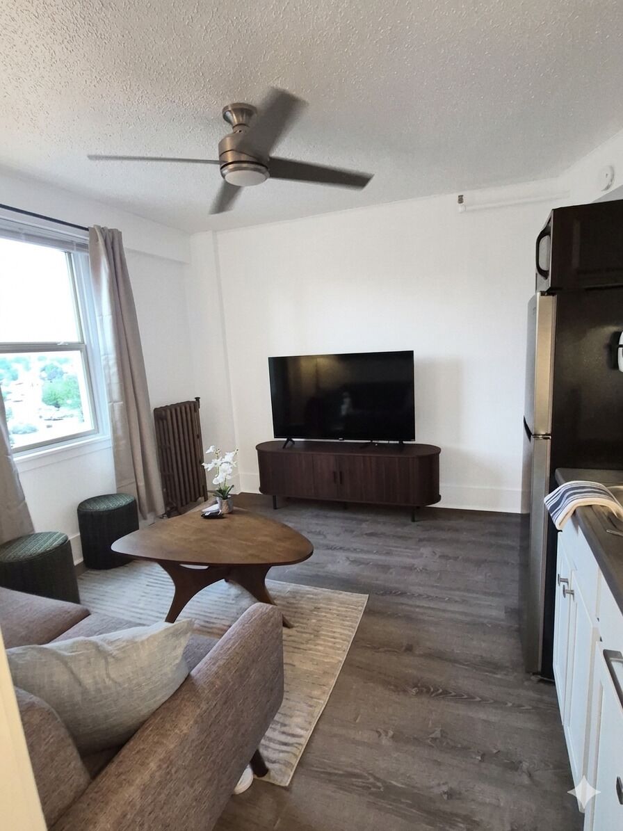 A modern living room with a flat-screen TV, a ceiling fan, and a dining area.