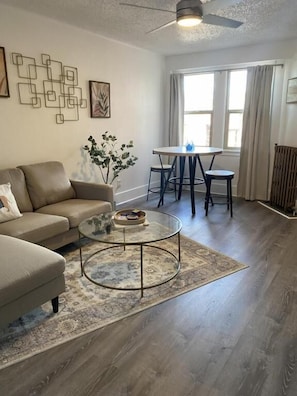 A living room with a sofa, coffee table, and a dining area with a table and chairs.