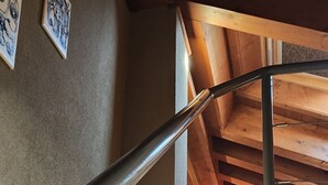 A multi-level wooden interior with a metal staircase, wooden beams, and a window.