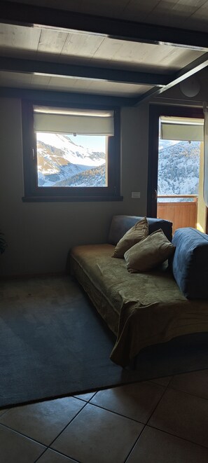 A bedroom with a bed, two windows, and a view of snow-covered mountains. - PeakView Mansarda Vacanze a Livigno 2123 slm - L'emozione di toccare il cielo! (Livigno)