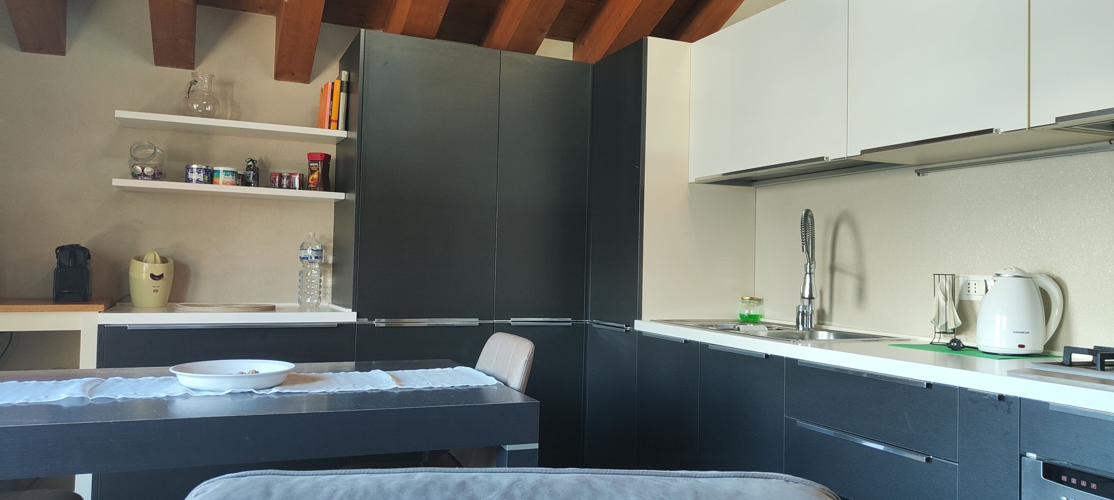 Een kleine keuken met een eettafel, een waterkoker en een koffiezetapparaat.