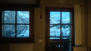 A room with two windows, each with a view of snow-covered mountains.