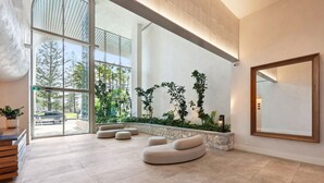 Una hall moderna con ampie finestre, un muro di pietra con fioriere e un grande specchio.