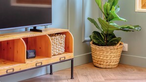 A wooden entertainment unit with a flat-screen TV, a woven basket, and a potted plant. - Raf & Liza, sublime F2 proche Vieux-Marché (Rouen)