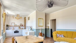 A modern kitchen with white cabinets, a dining area with a wooden table and chairs, a yellow sofa, and a unique ceiling light fixture. - Raf & Liza, sublime F2 proche Vieux-Marché (Rouen)