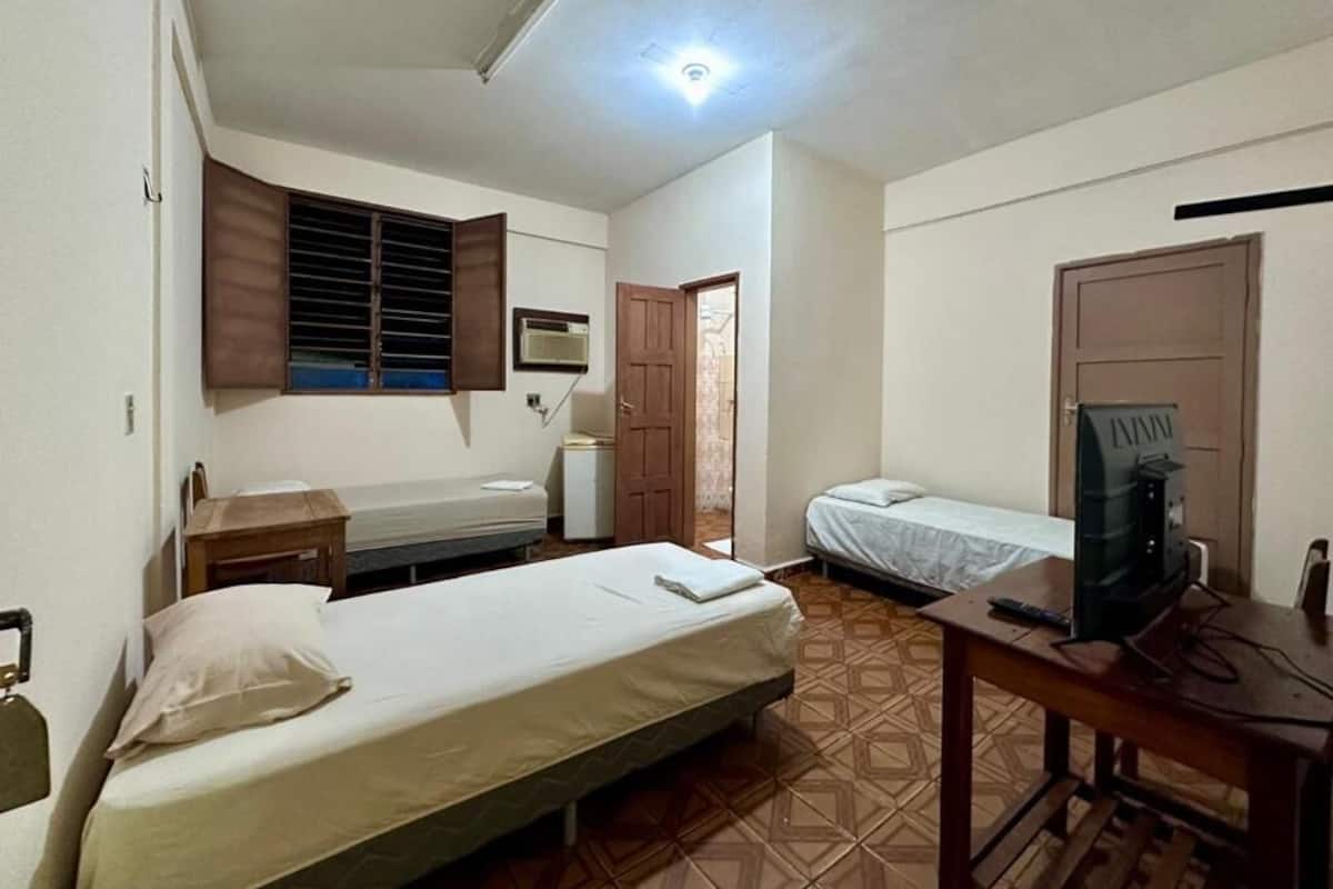 Una habitación con cama, escritorio, silla, televisor y armario.