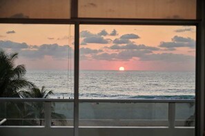 A sunset view from a window overlooking the ocean. - Apartment Beachfront view. (Puerto Escondido)