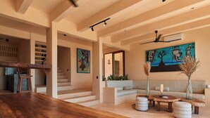 Un'ampia zona giorno con un tavolo da pranzo in legno, un divano e una scala che conduce a un piano superiore.