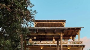 Un edificio a due piani con un balcone in legno, ampie finestre e un vialetto sterrato.