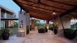A covered outdoor area with a thatched roof, potted plants, and a seating area.