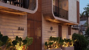 A modern building with a balcony, a thatched roof, and a sign reading 'Casa Nado.'