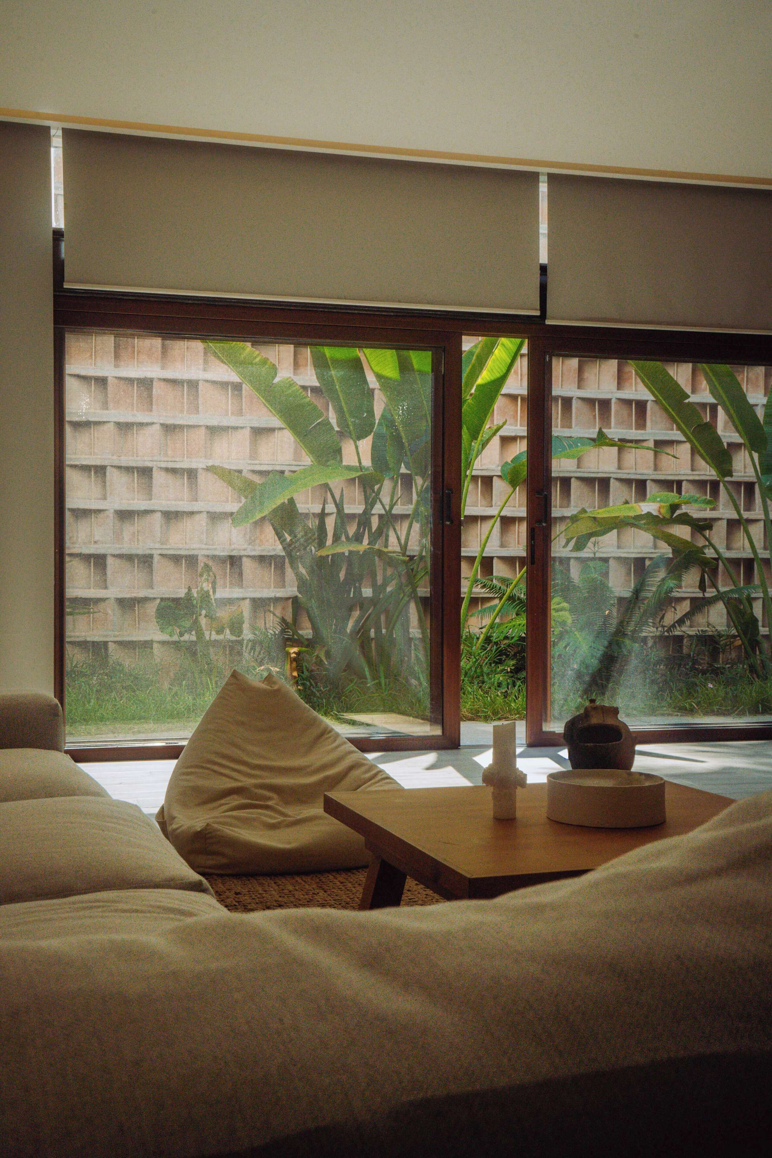 A room with a large window, a sofa, a small table, and a decorative vase.