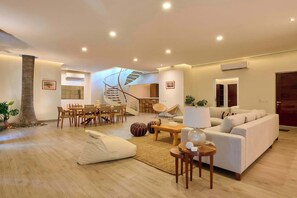 Un salon moderne avec un escalier en colimaçon, un coin repas et un ensemble de canapés.