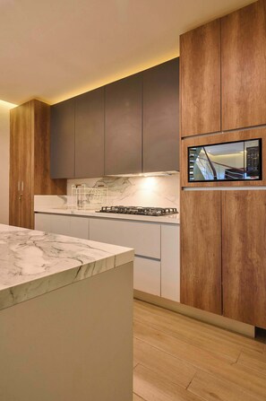 A modern kitchen with a marble countertop, wooden cabinets, and a built-in microwave. - Casa rosa · La casa rosa de Zicatela / Top-tier beachouse (Puerto Escondido)