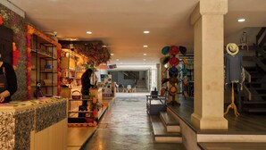 A spacious corridor with a reception desk, shelves with various items, and a staircase leading to an upper level. - Historic Center Hotel - Walk to Santo Domingo Temple (Oaxaca de Juárez)