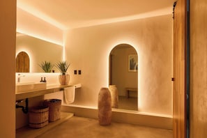 Une salle de bain avec un lavabo, un miroir et deux grands vases.